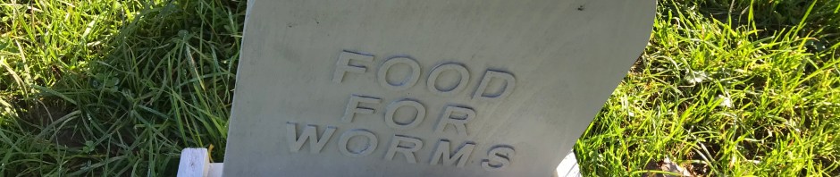 A gravestone saying 'Food for worms' filled with worms.